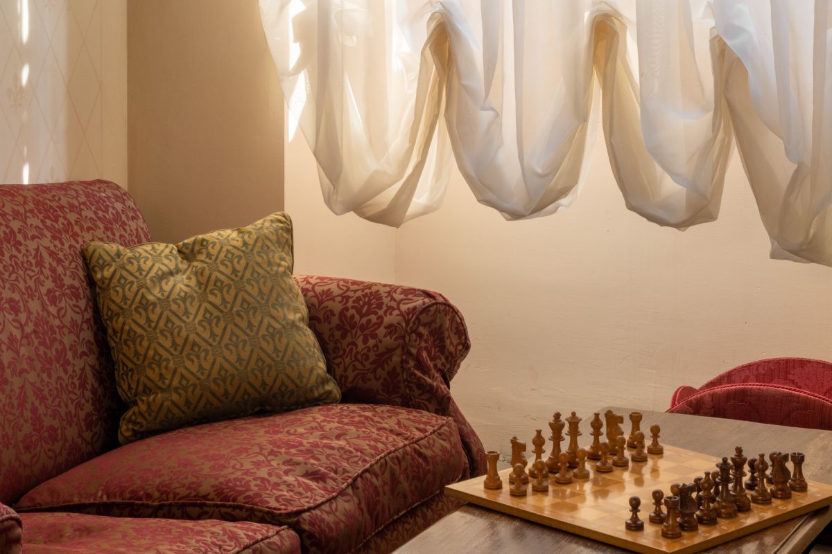 Lounge detail with classic sofa, chess table and soft light in a historic Tuscan residence - La Collegiata, BZAR hotels in Tuscany