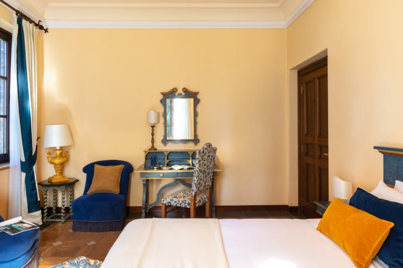Camera deluxe con scrittoio elegante, poltrona blu e ambienti di charme per soggiorni esclusivi in Toscana - La Collegiata, BZAR hotels in Toscana
