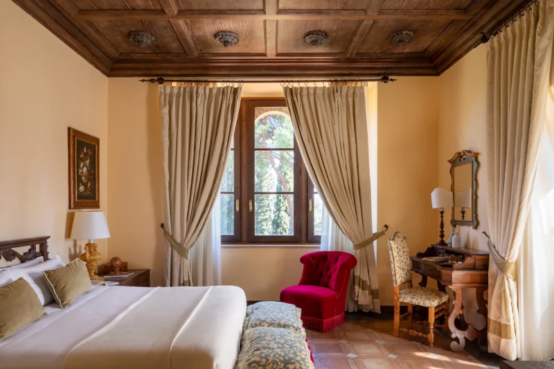 Junior Suite with decorated wooden ceiling, double bed, classic writing desk and red designer armchair - La Collegiata, BZAR hotels in Tuscany