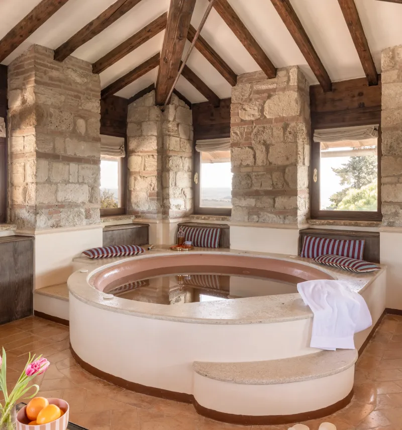Whirlpool tub in La Torre Master Suite with stone walls and views over the Tuscan countryside - La Collegiata, BZAR hotels in Tuscany