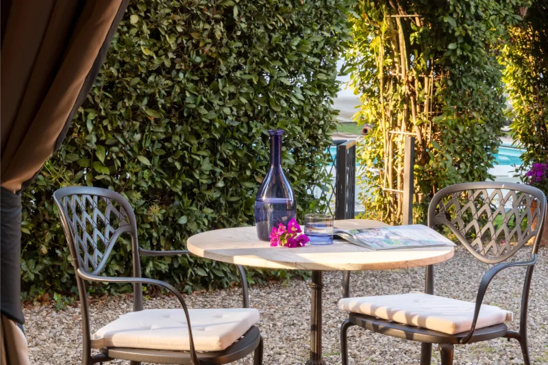 Private patio of the superior room with outdoor table and chairs surrounded by Tuscan countryside greenery - La Collegiata, BZAR hotels in Tuscany