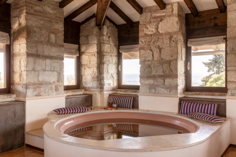 Whirlpool tub in La Torre Master Suite with stone walls and views over the Tuscan countryside - La Collegiata, BZAR hotels in Tuscany