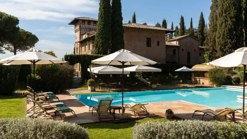 View of the pool with lounge chairs and umbrellas - La Collegiata, BZAR hotels in Tuscany
